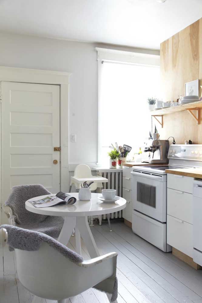 Cette petite cuisine blanche a mis en détail le bois dans le placard et le comptoir de l'évier