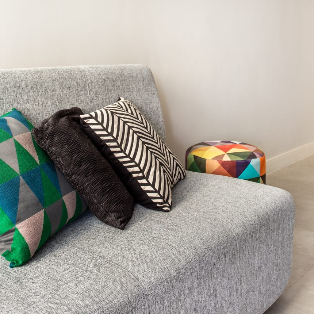 Canapé gris avec des oreillers colorés en appartement dépouillé