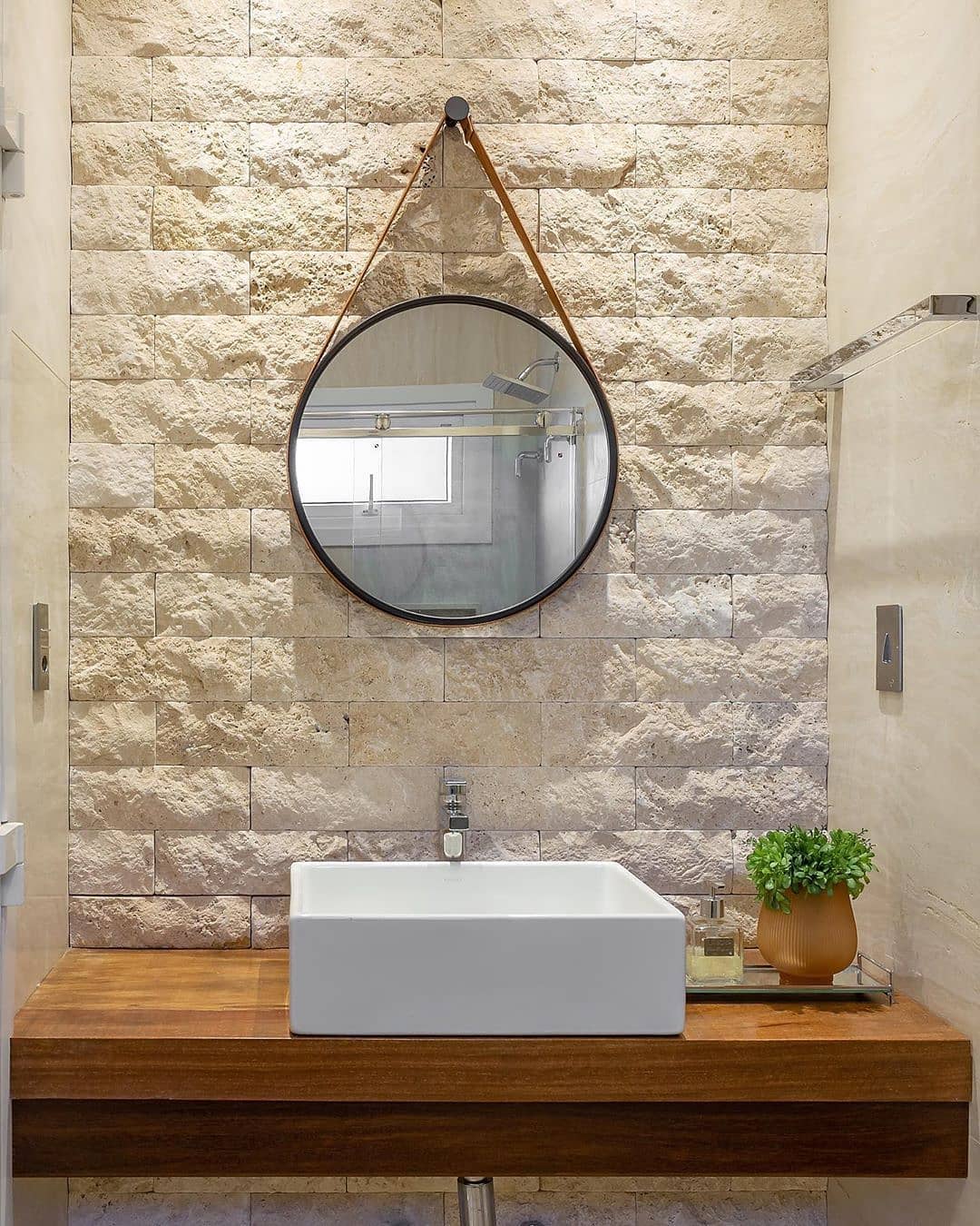 miroir adnet rond dans la salle de bain avec revêtement en pierre