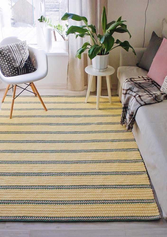 Le tapis au crochet rayé jaune et gris couvre toute la longueur de la pièce