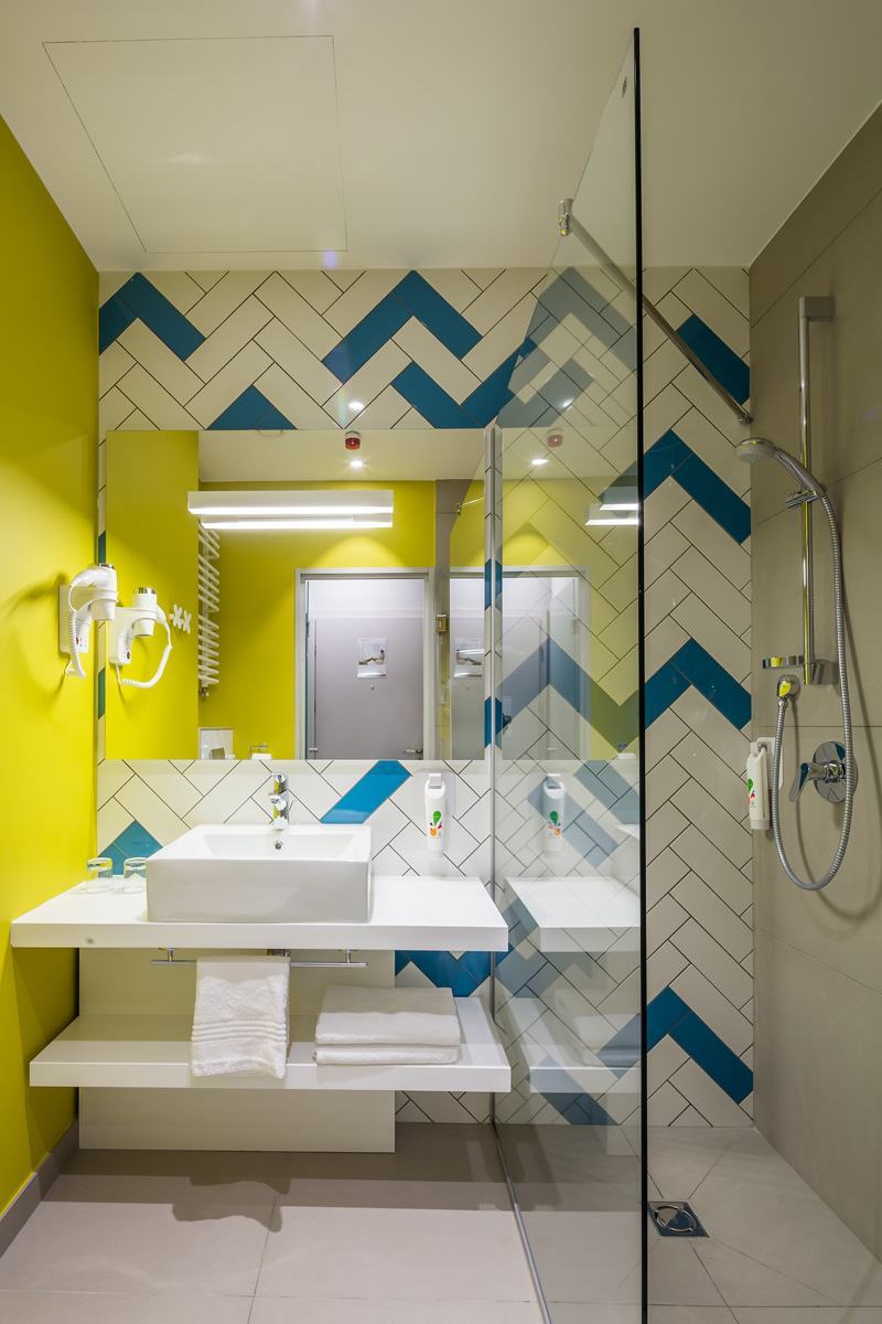 Utiliser des couleurs vives dans la salle de bain est toujours bon, mais équilibrez-le avec le blanc pur du comptoir.
