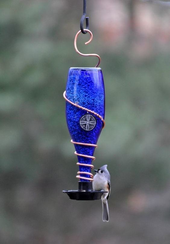 Support en métal avec bouteille en verre pour stocker les graines pour oiseaux.