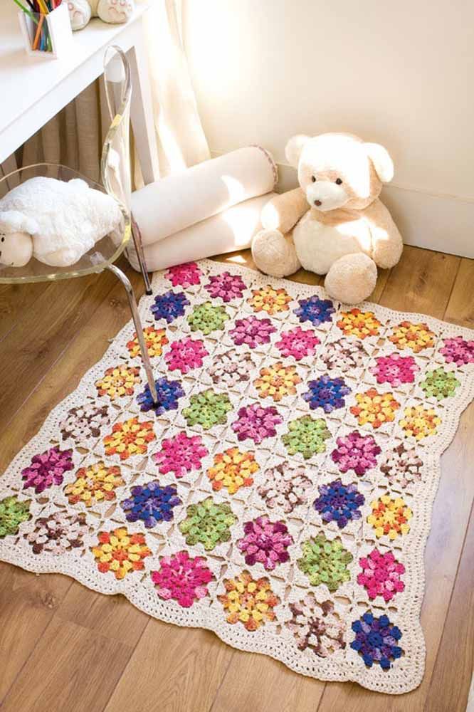 Des carrés au crochet avec des fleurs forment ce beau et délicat tapis pour la chambre de bébé