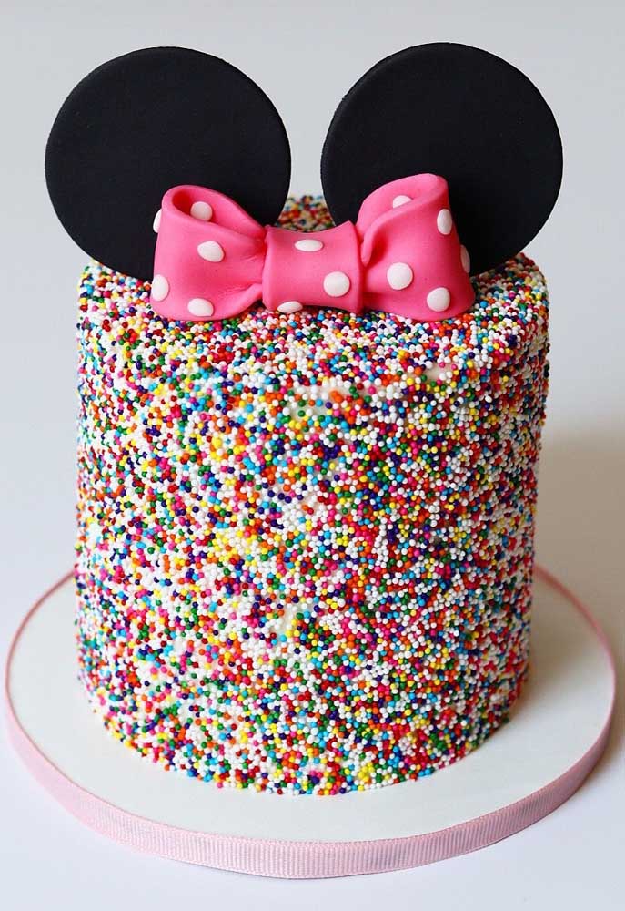 Gâteau Minnie décoré de paillettes colorées.  Pour caractériser le thème, petites oreilles et nœud sur le dessus