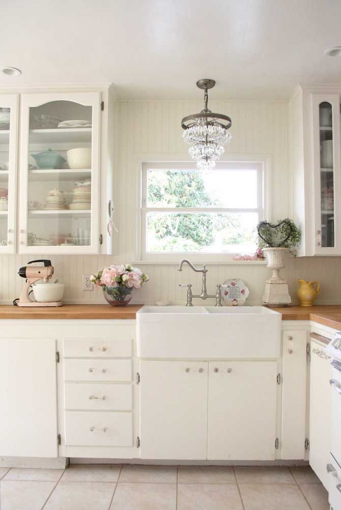 La cuisine blanche est venue dans le style Shabby Chic avec des fleurs délicates sur le comptoir, un mélangeur vintage et un vase en céramique usé à côté